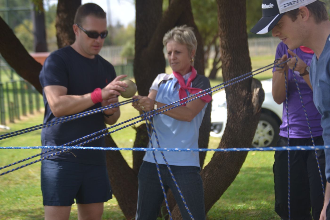 Team members working together in a rope trust exercise